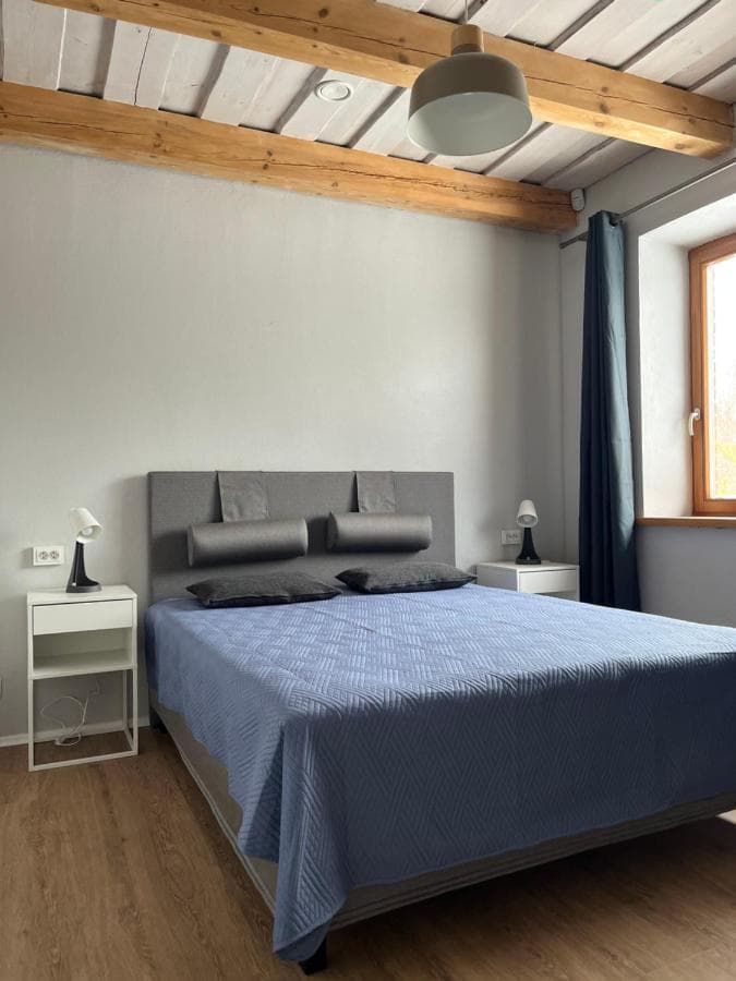 Miegamasis su didele dvigule lova ir medinėmis sijomis lubose