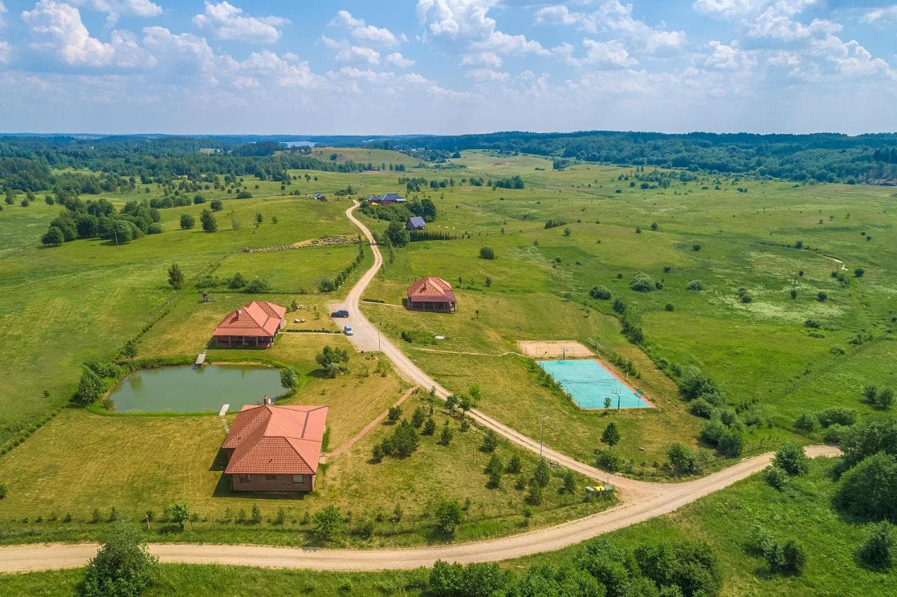 Sodybos vaizdas iš paukščio skrydžio — namai, pieva ir teniso aikštelė