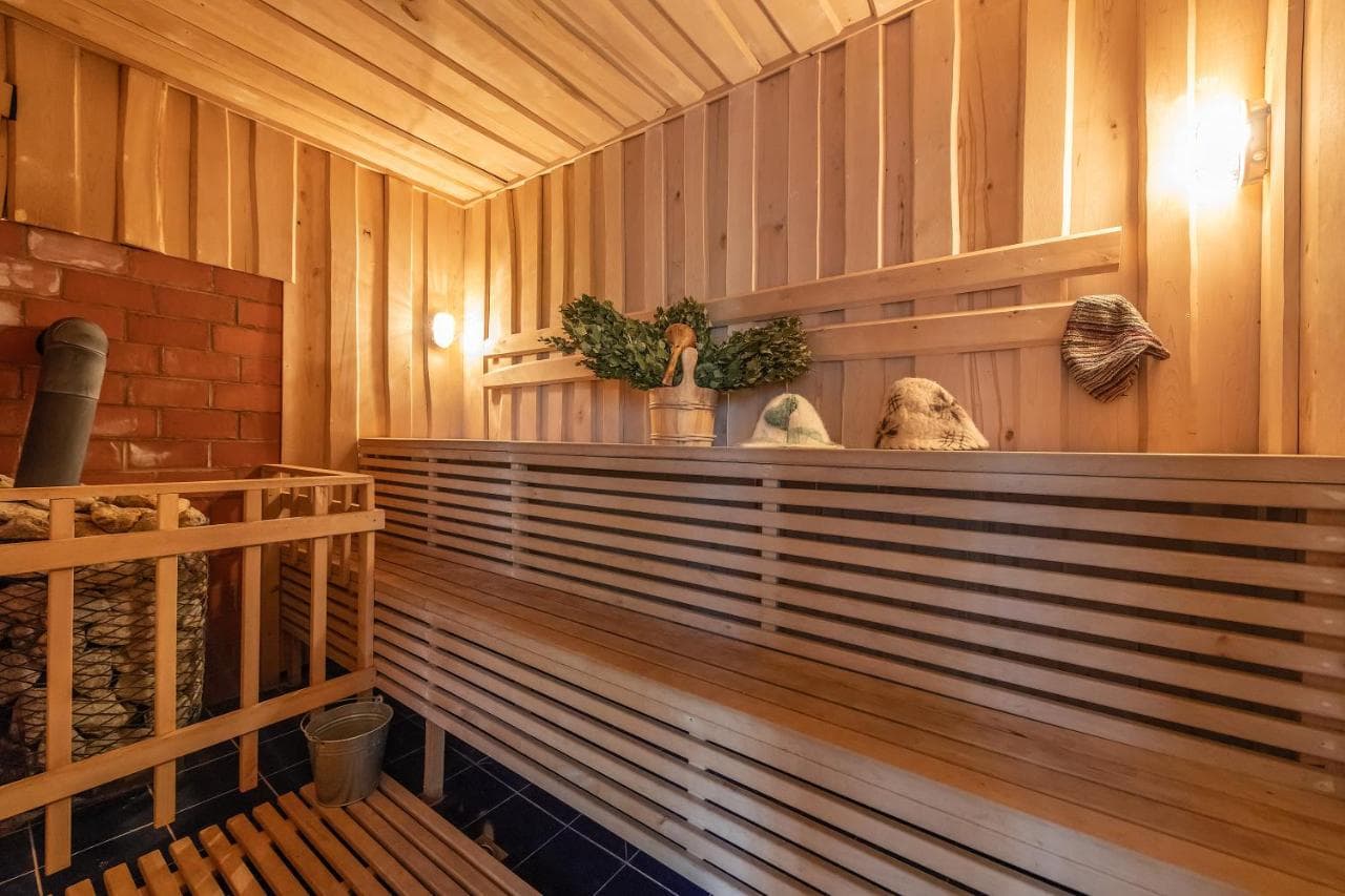 Pirties vidus su šviesaus medžio lentomis, akmenų krosnele ir beržo vantomis