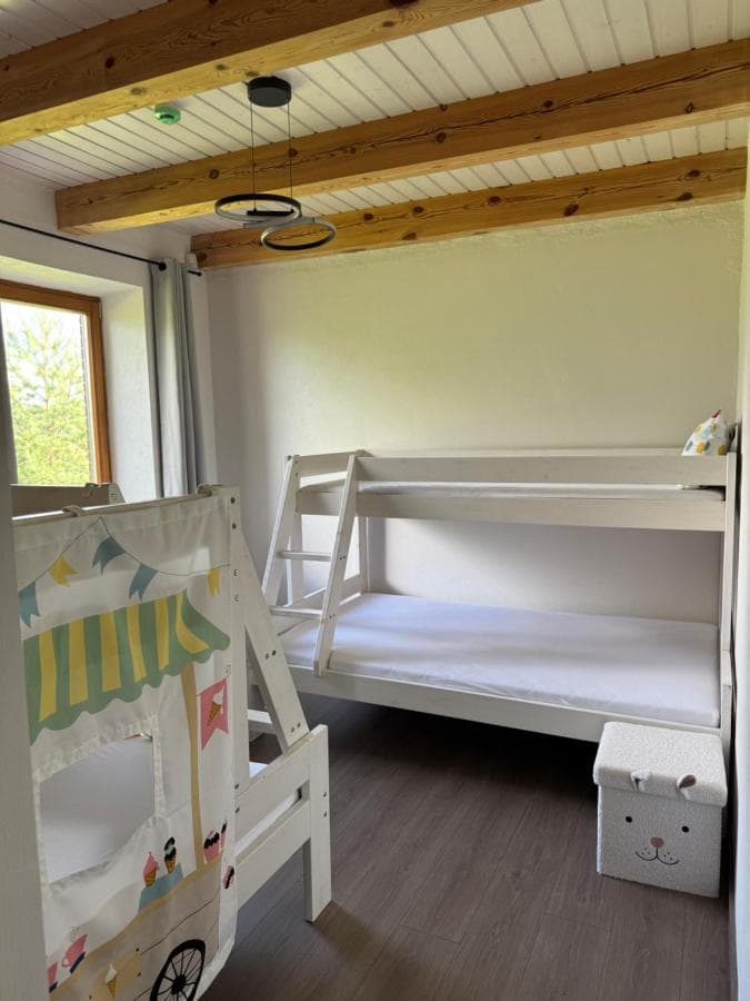 Miegamasis su didele dvigule lova ir medinėmis sijomis lubose