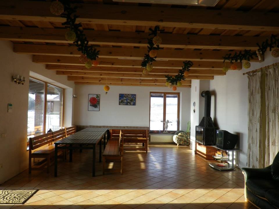 Salė paruošta šventei — ilgi stalai, žvakės, krosnelė