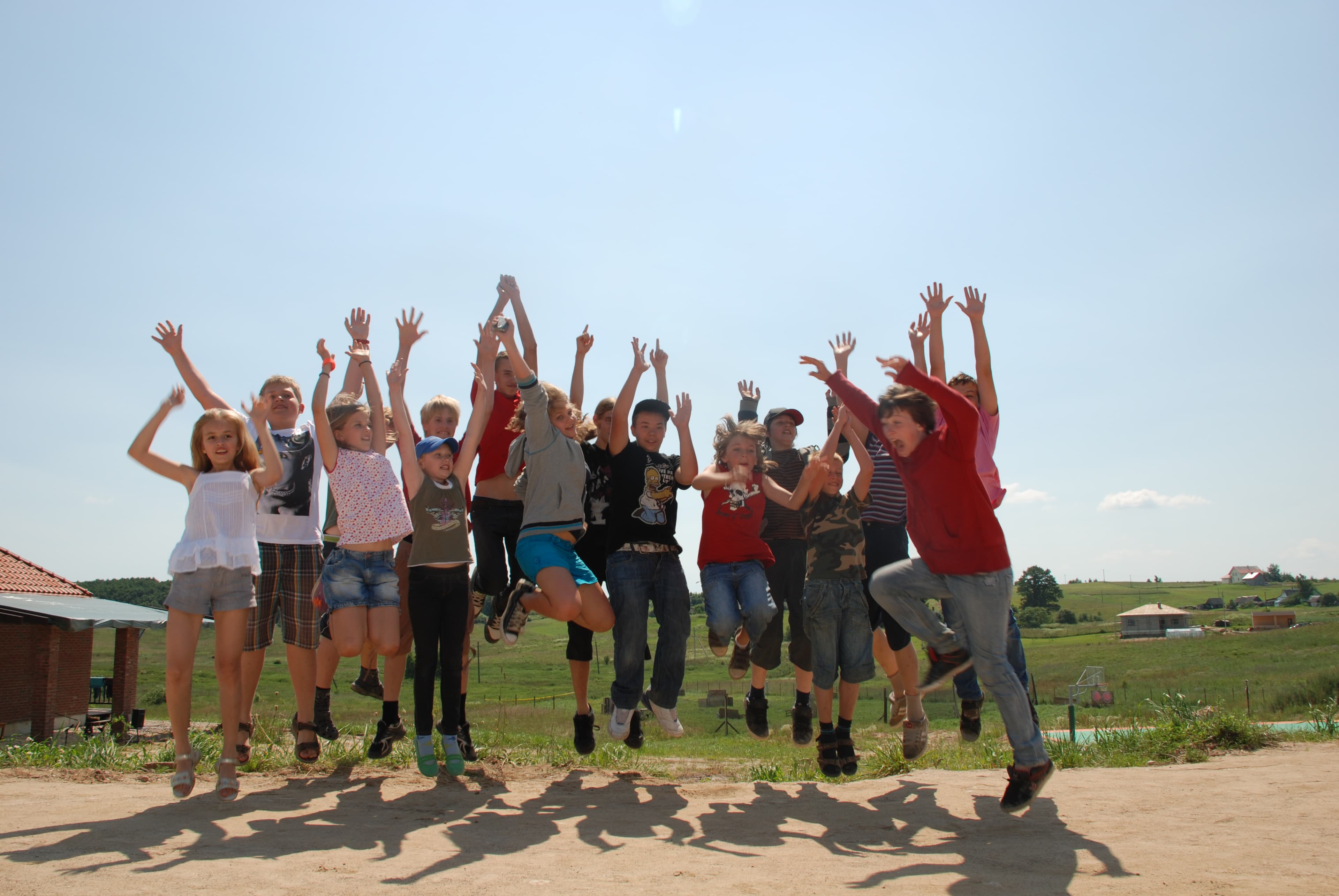 Vaikų grupė šokinėja kieme vasaros saulutėje