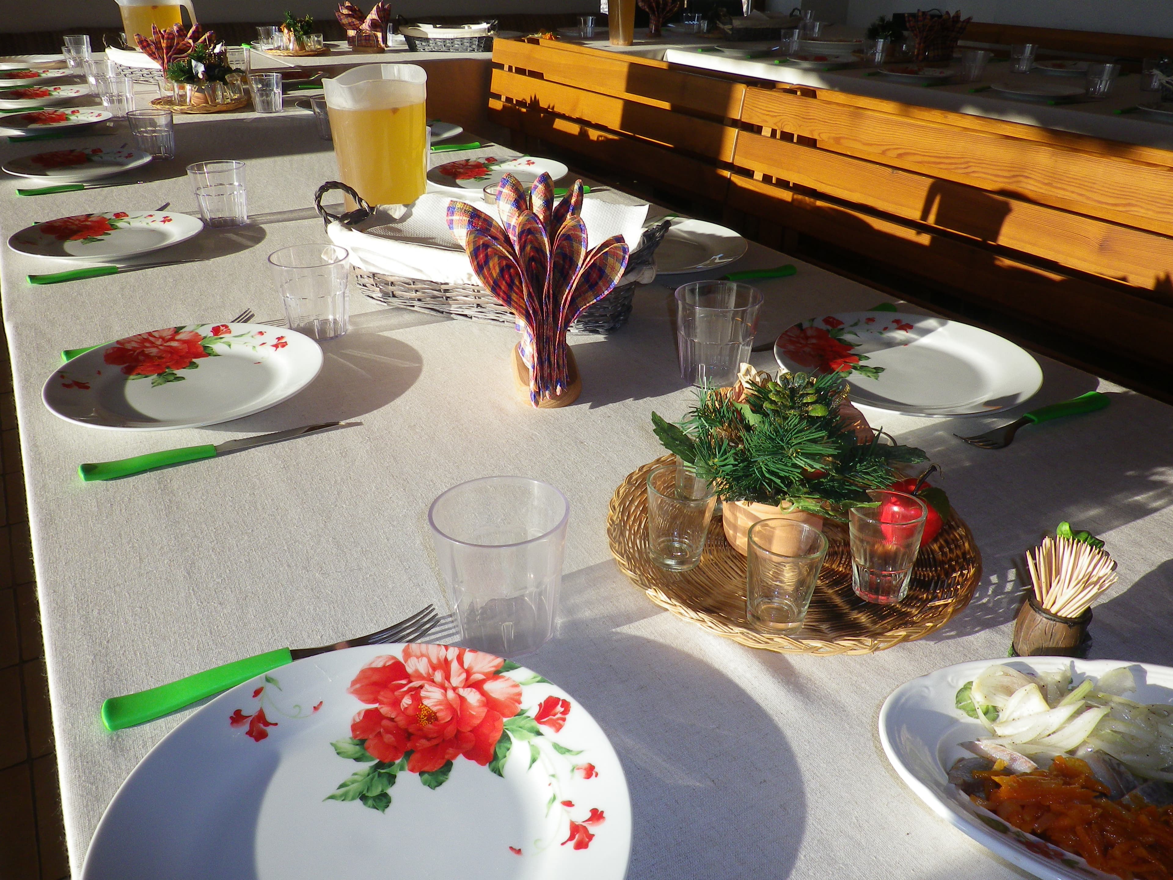 Šventinis stalas su gėlėtomis lėkštėmis ir vaišėmis